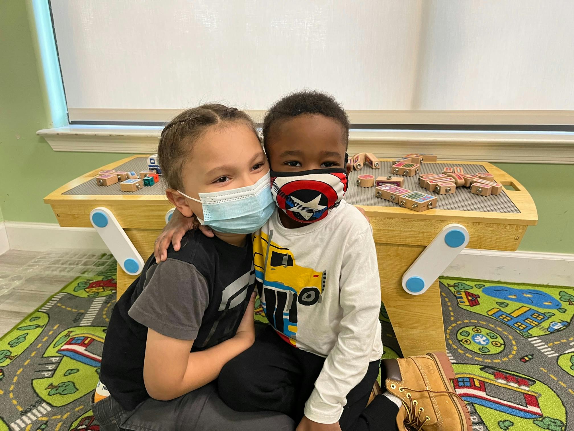 Two children wearing face masks, one with arm around the other