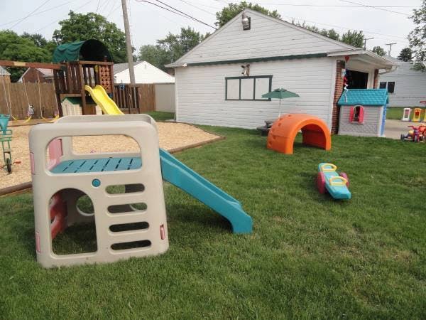 Outdoor playground with a small slide, playhouse, and climbing structure