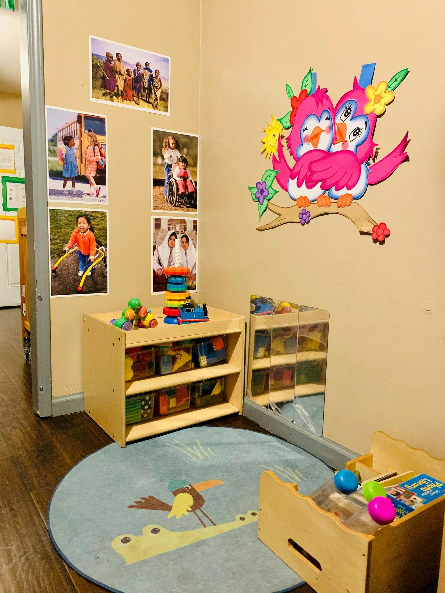 Playroom with photos on wall, toy shelves, and a rug with an alligator design