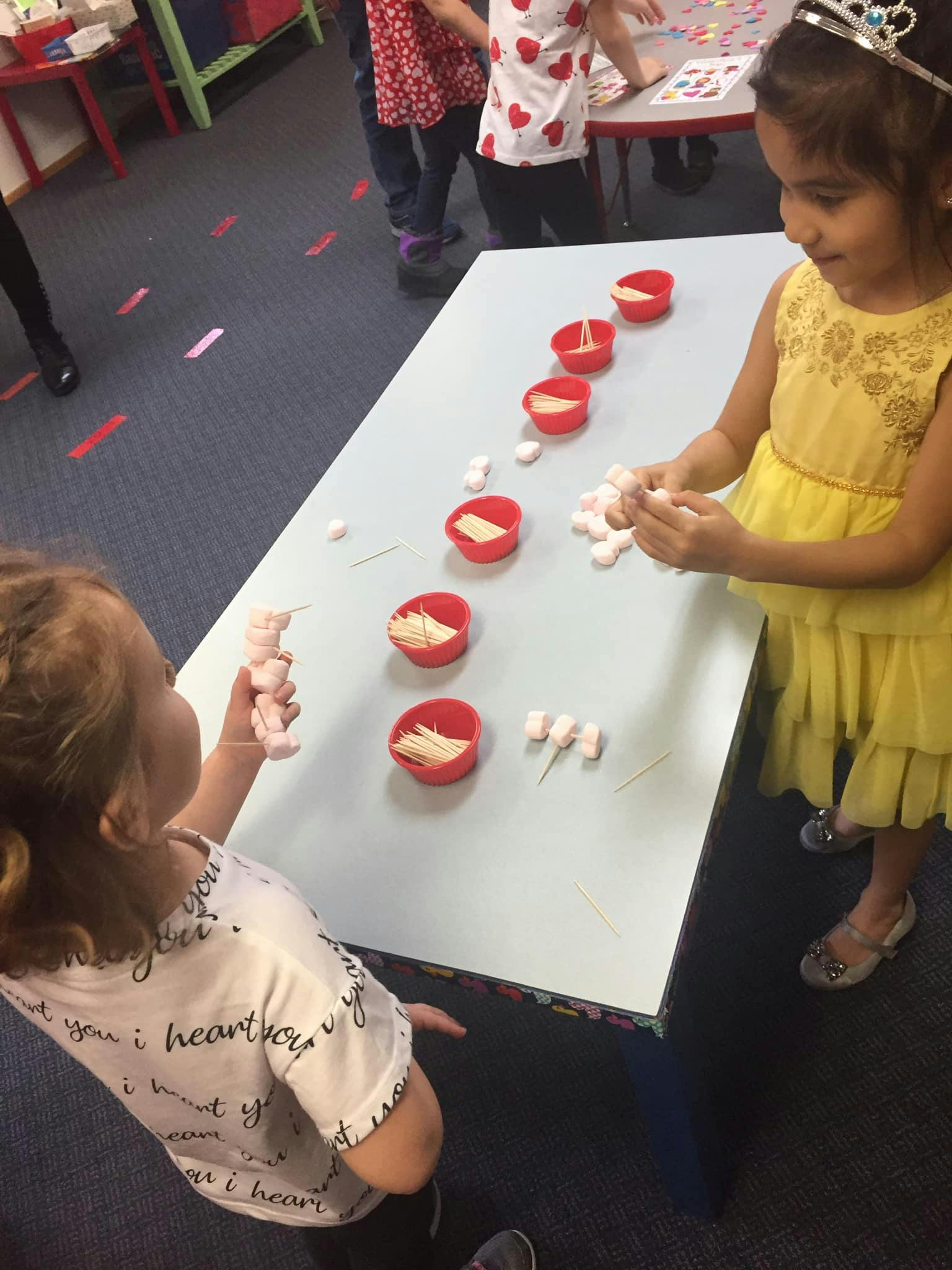 Two children playing with craft supplies at a table