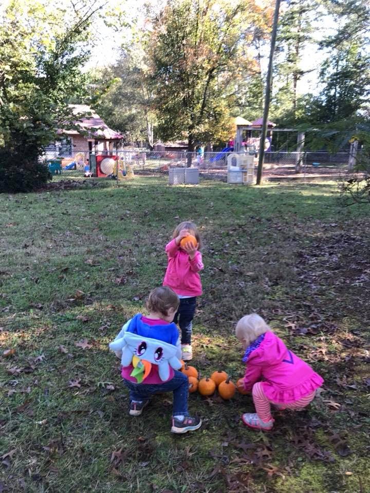 Three children playing with small pumpkins on the grass