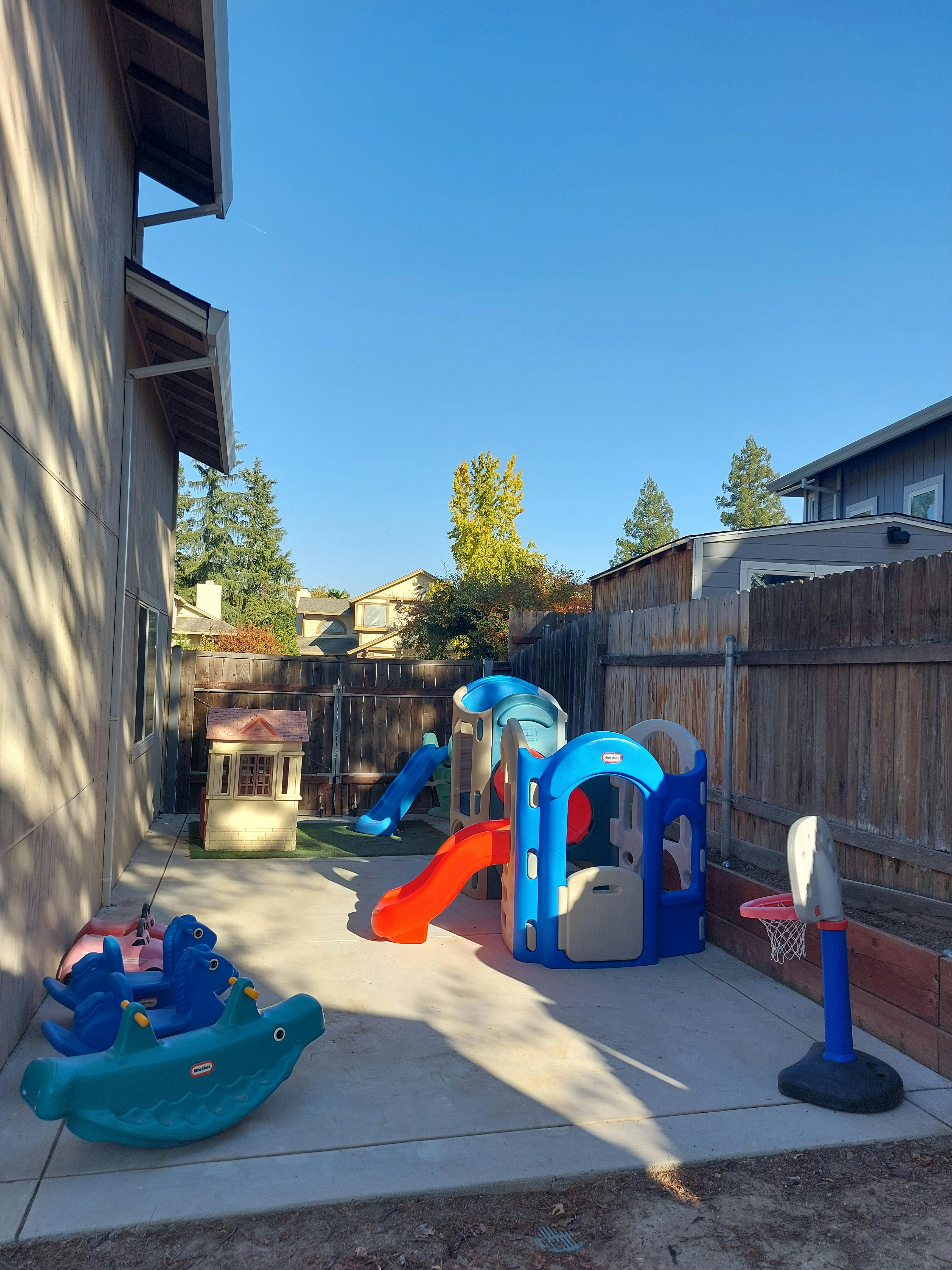 Outdoor play area with slides, playhouse, and basketball hoop