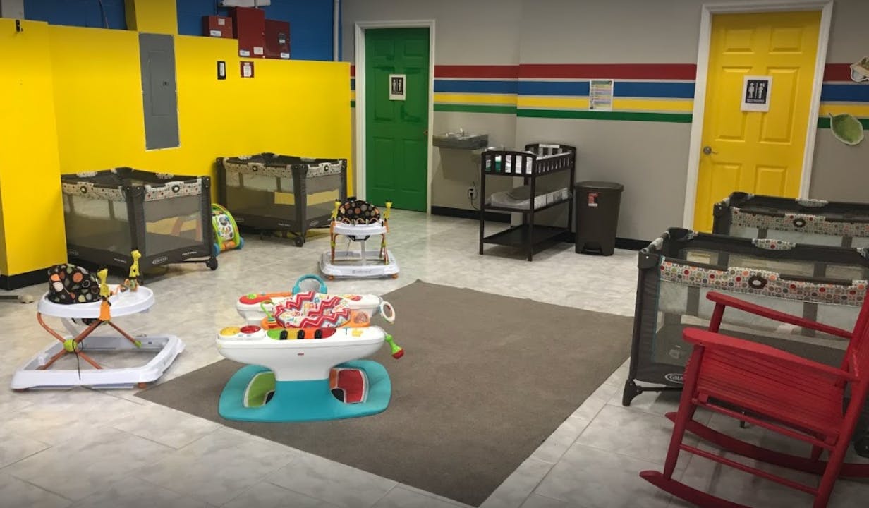 Daycare room with cribs, baby walkers, and a red rocking chair