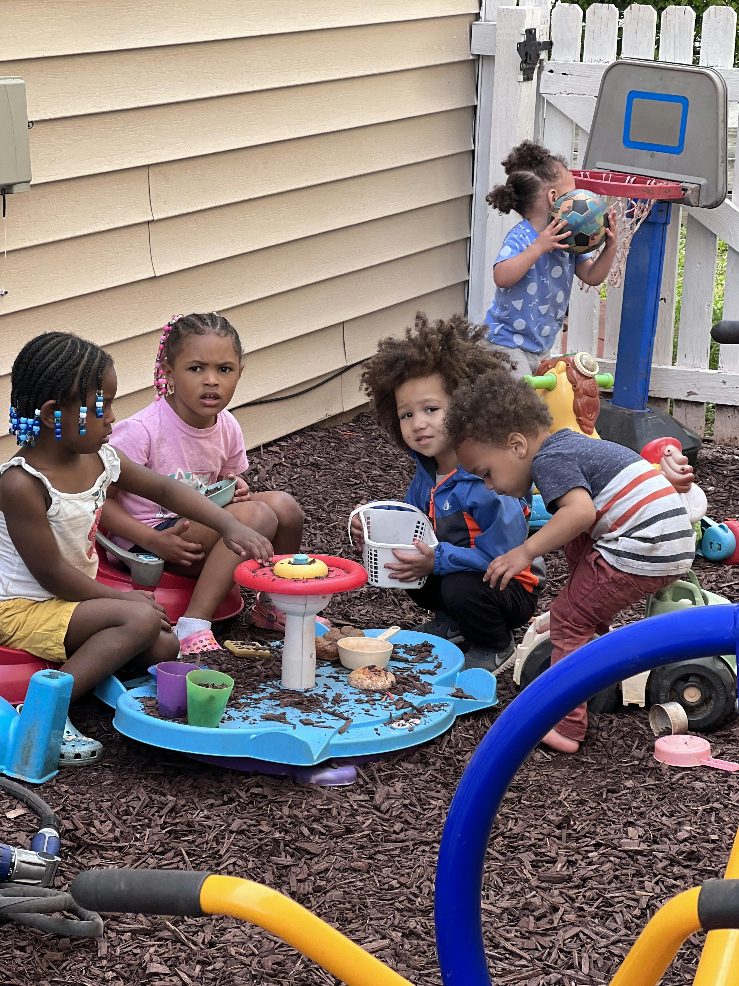 Children playing with toys in an outdoor area with wood chip mulch