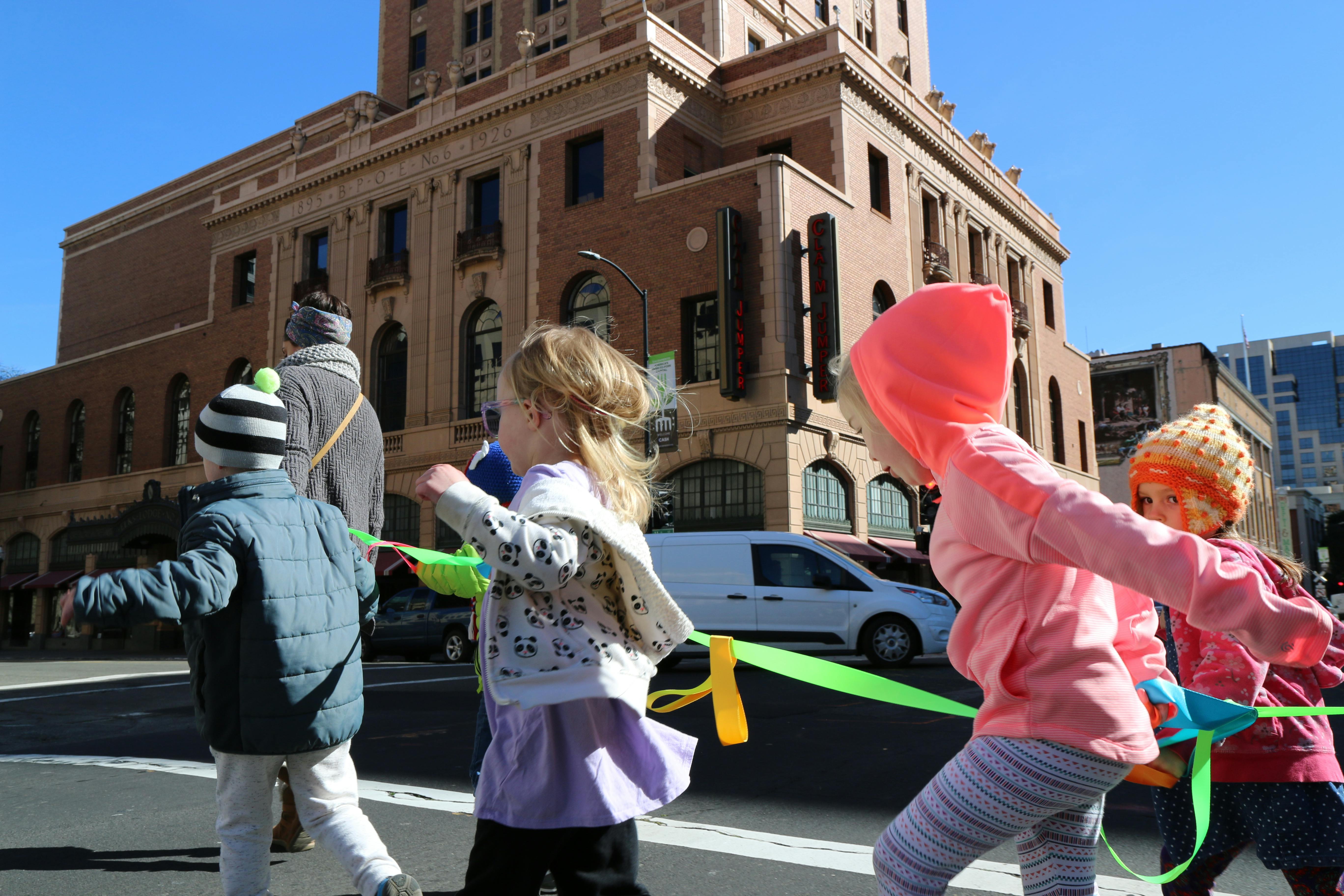 Children holding a green ribbon on a city street