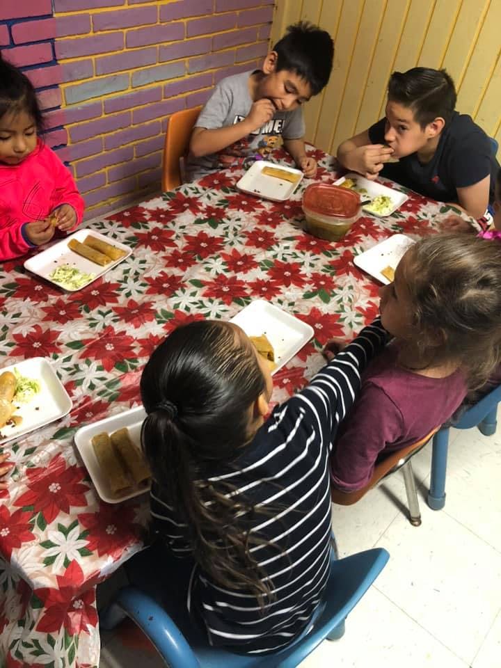 Children eating at a table with a floral tablecloth