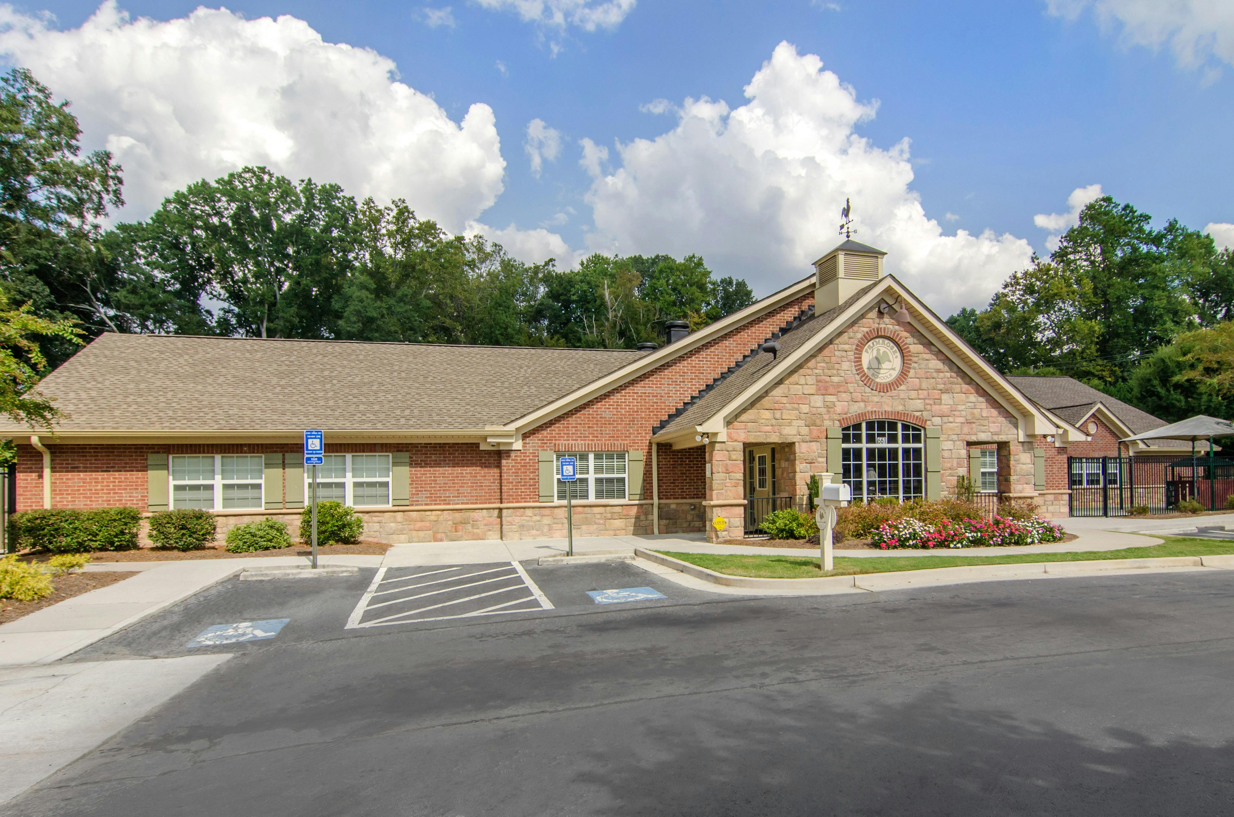 Brick and stone school building with a parking lot and trees