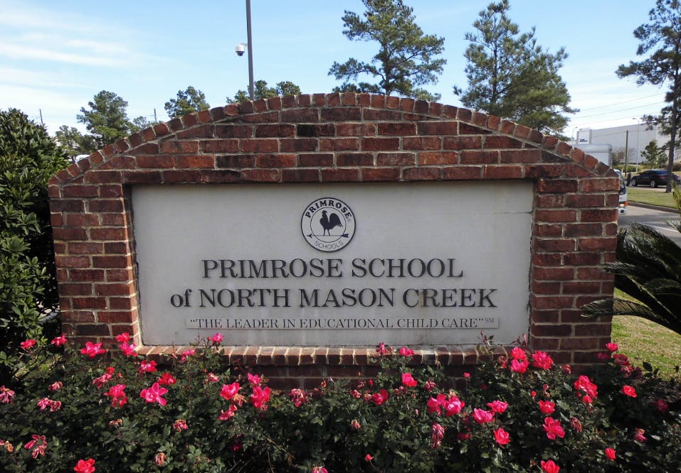 Brick sign for Primrose School of North Mason Creek with pink flowers