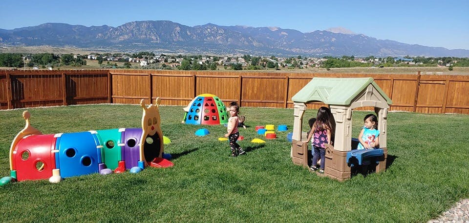 Children playing with outdoor toys in a grassy yard