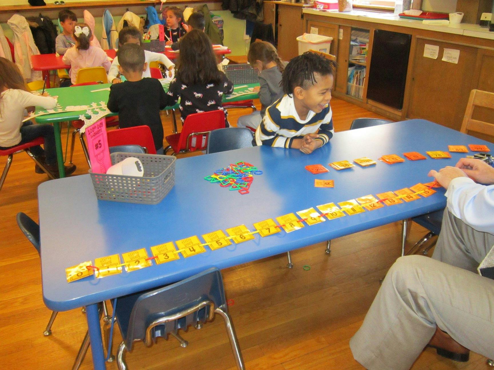 Child and adult at a table with learning materials in a classroom