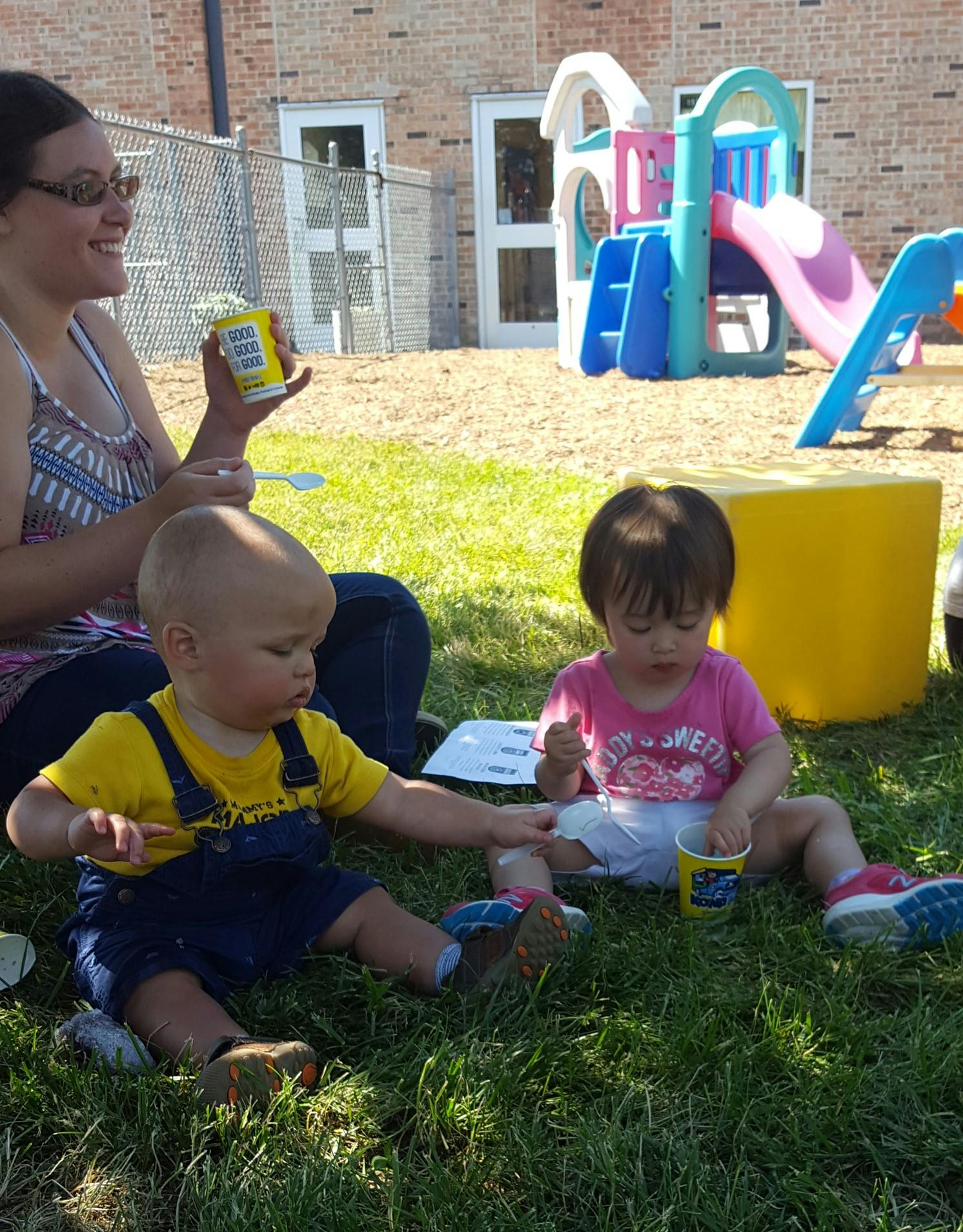 Person and two children sitting on grass outdoors