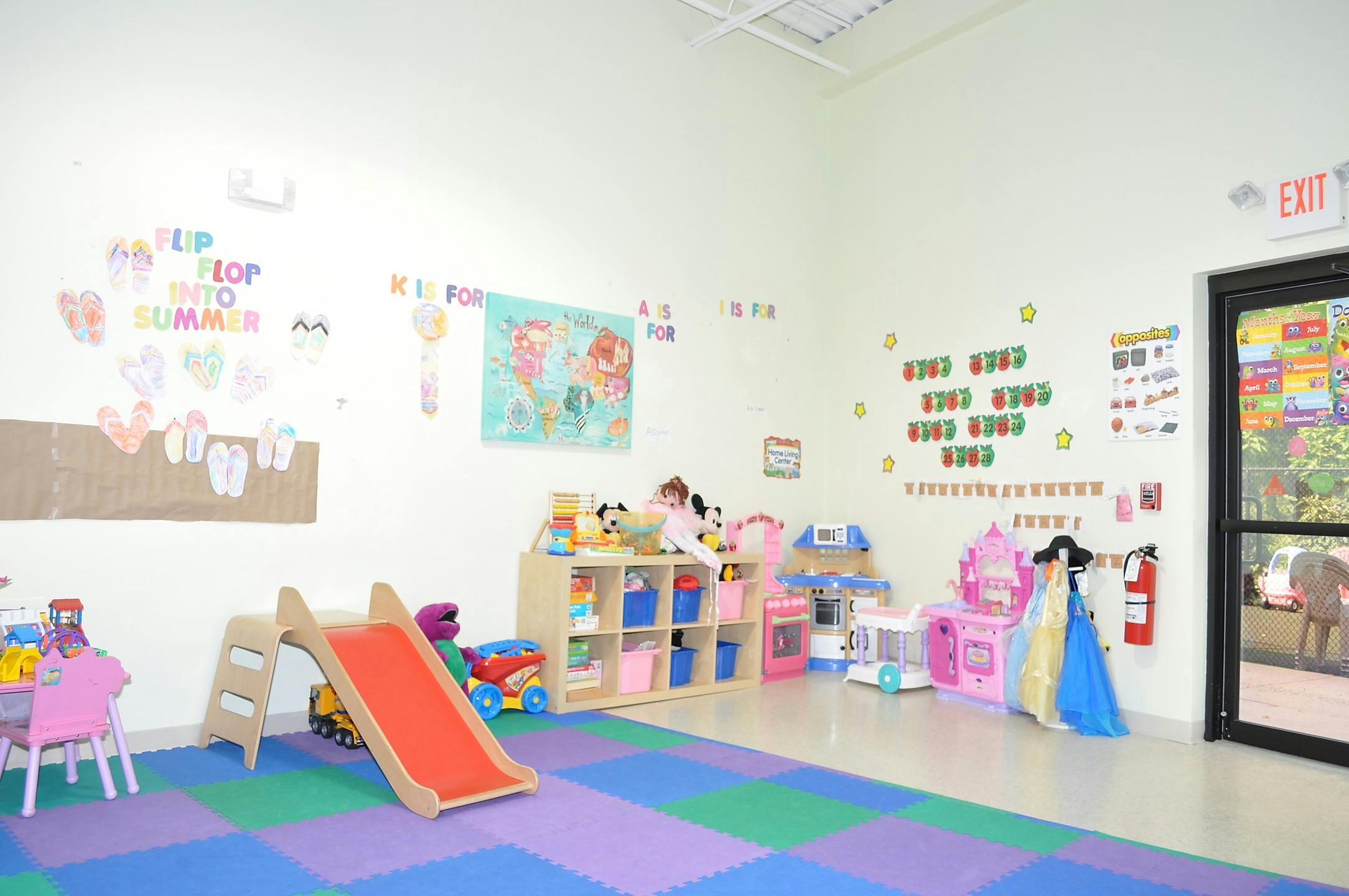 Playroom with a small slide, toy shelves, and colorful floor mats
