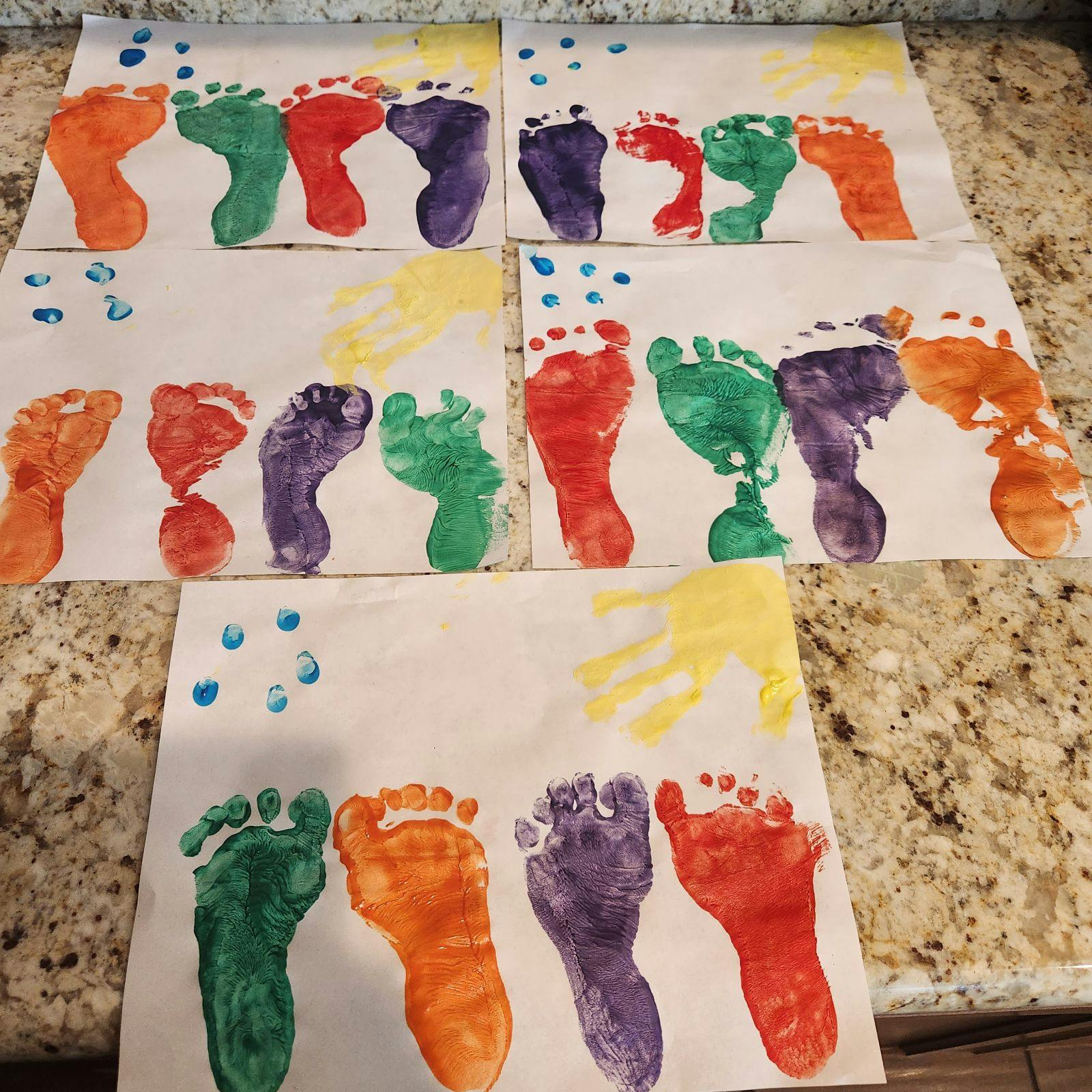 Colorful painted footprints and handprints on white paper sheets