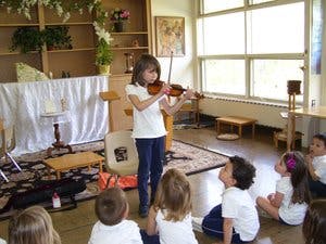 Child playing violin for other children