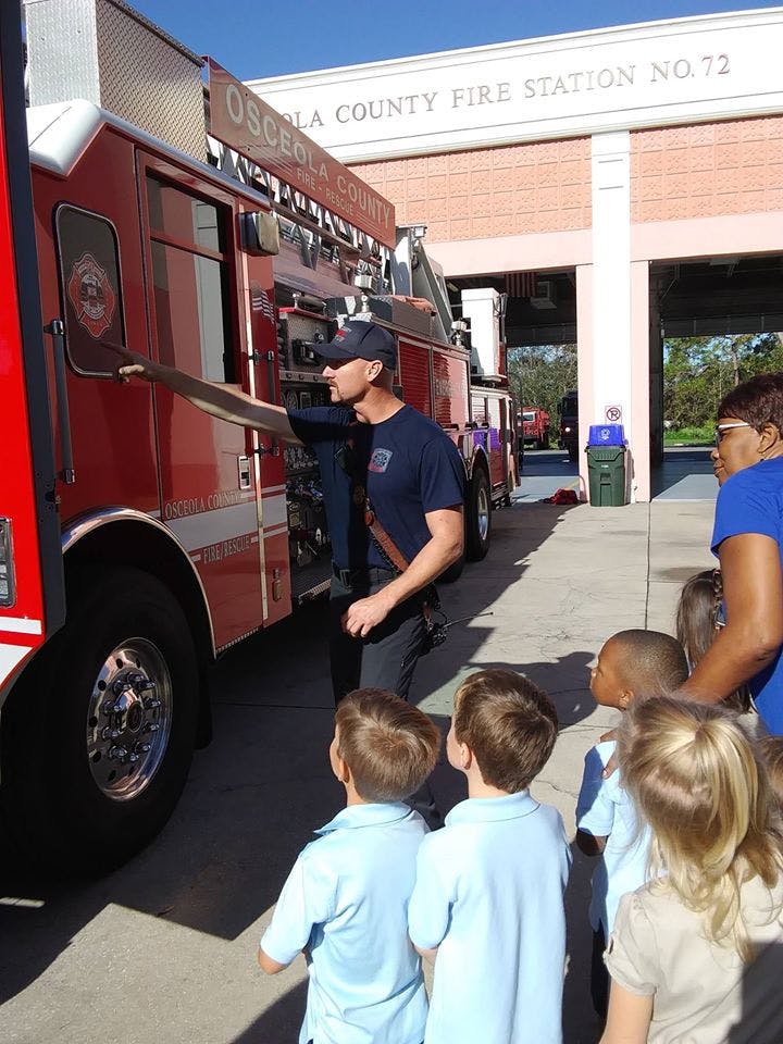 Person showing children a fire truck at a fire station