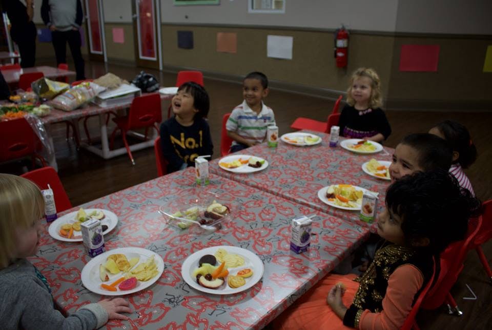 Children sitting at tables with plates of food