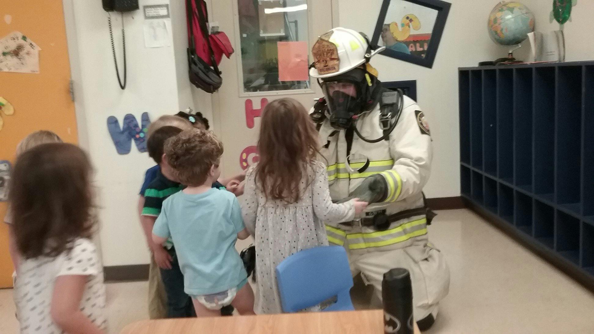 Firefighter kneeling and interacting with children in a classroom