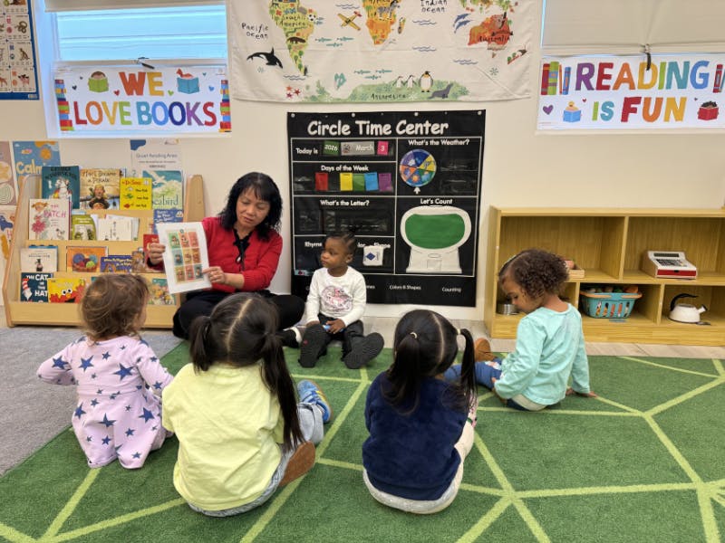 person reading a book to multiple children in a classroom