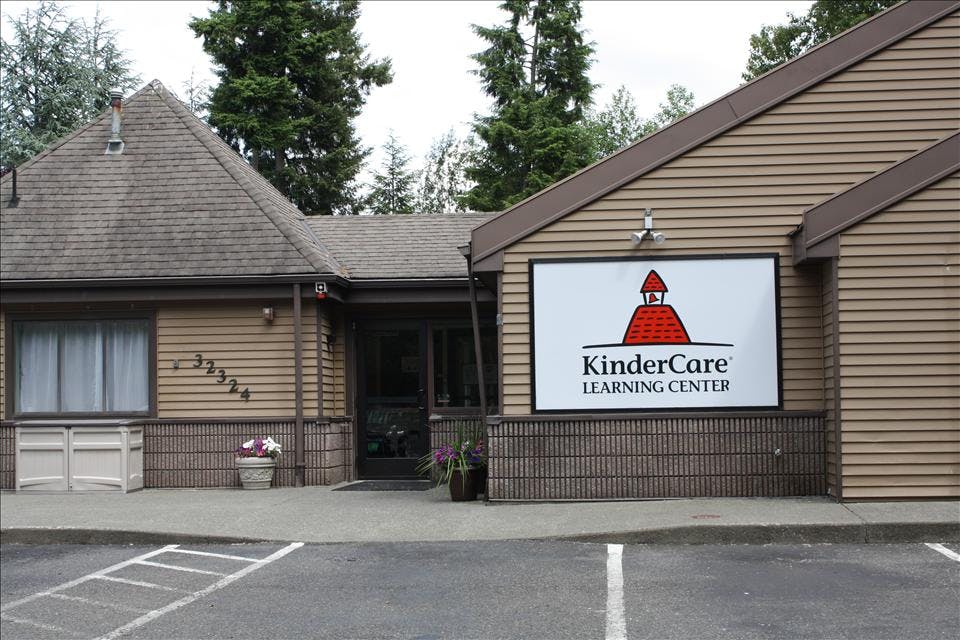 KinderCare Learning Center sign on a building exterior with trees in the background