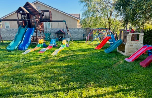 Playground with multiple slides and swings on a grassy lawn
