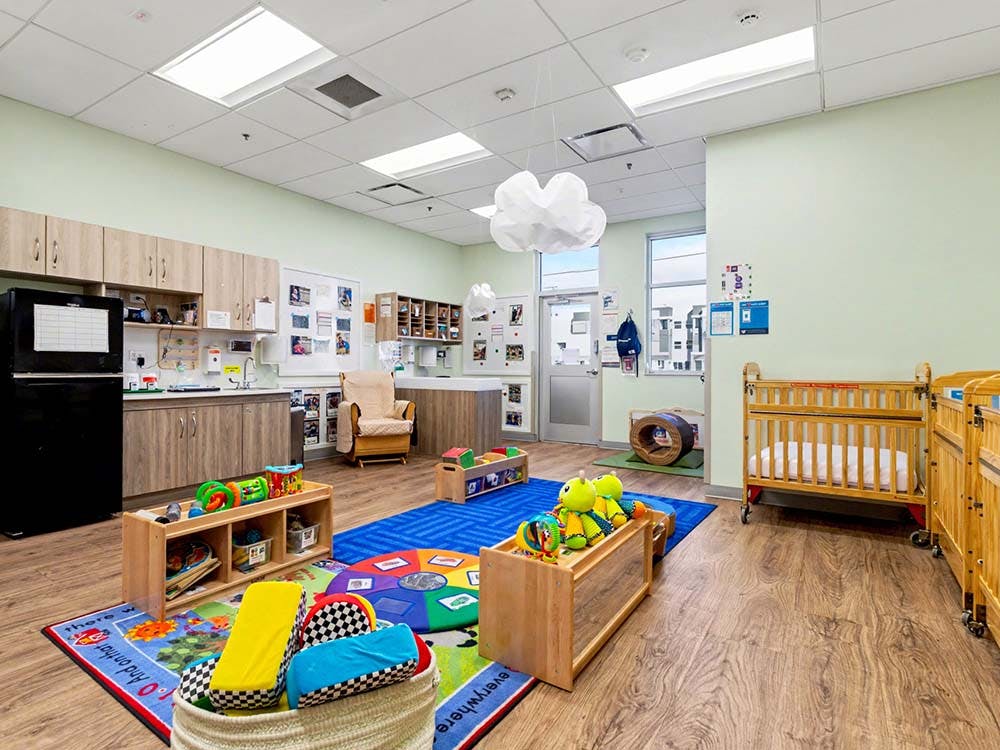 daycare classroom with cribs, play mats, and toys