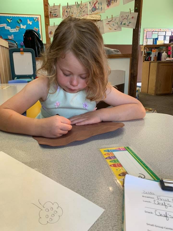 Child drawing on brown paper at a table