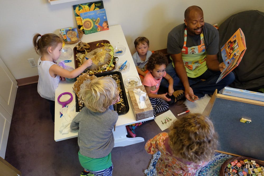 Adult reading to children while other children play at a table