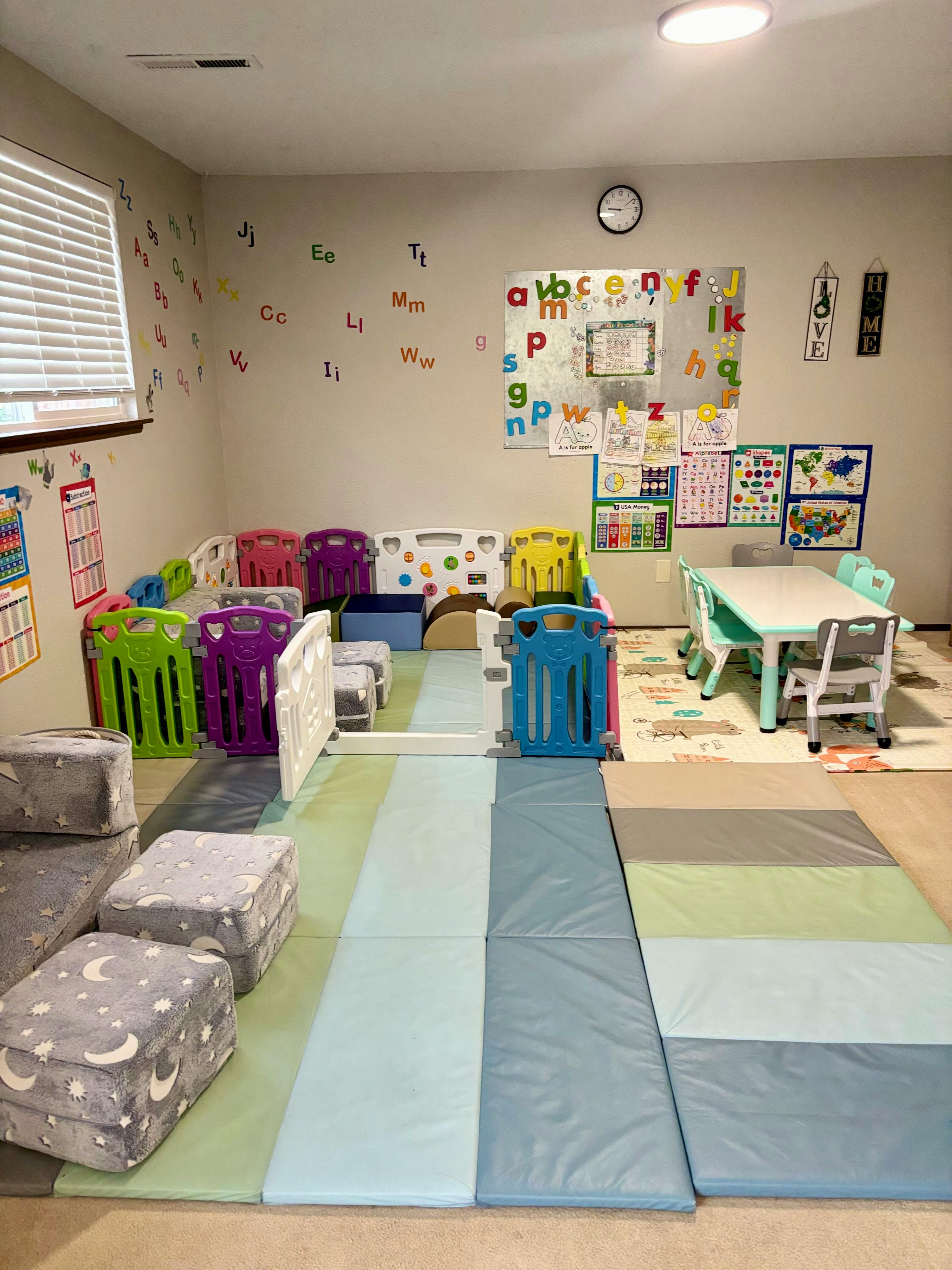 Playroom with colorful playpen, small table and chairs, and floor mats