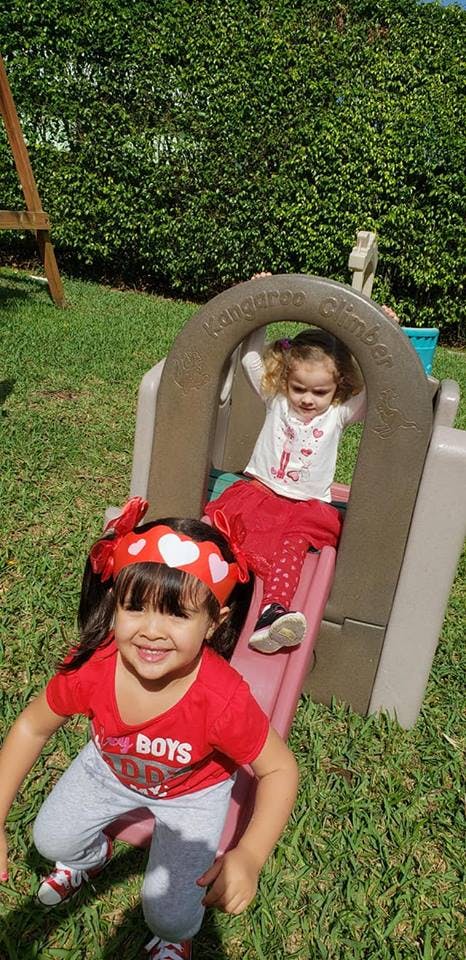 Two children playing on a slide in a grassy area