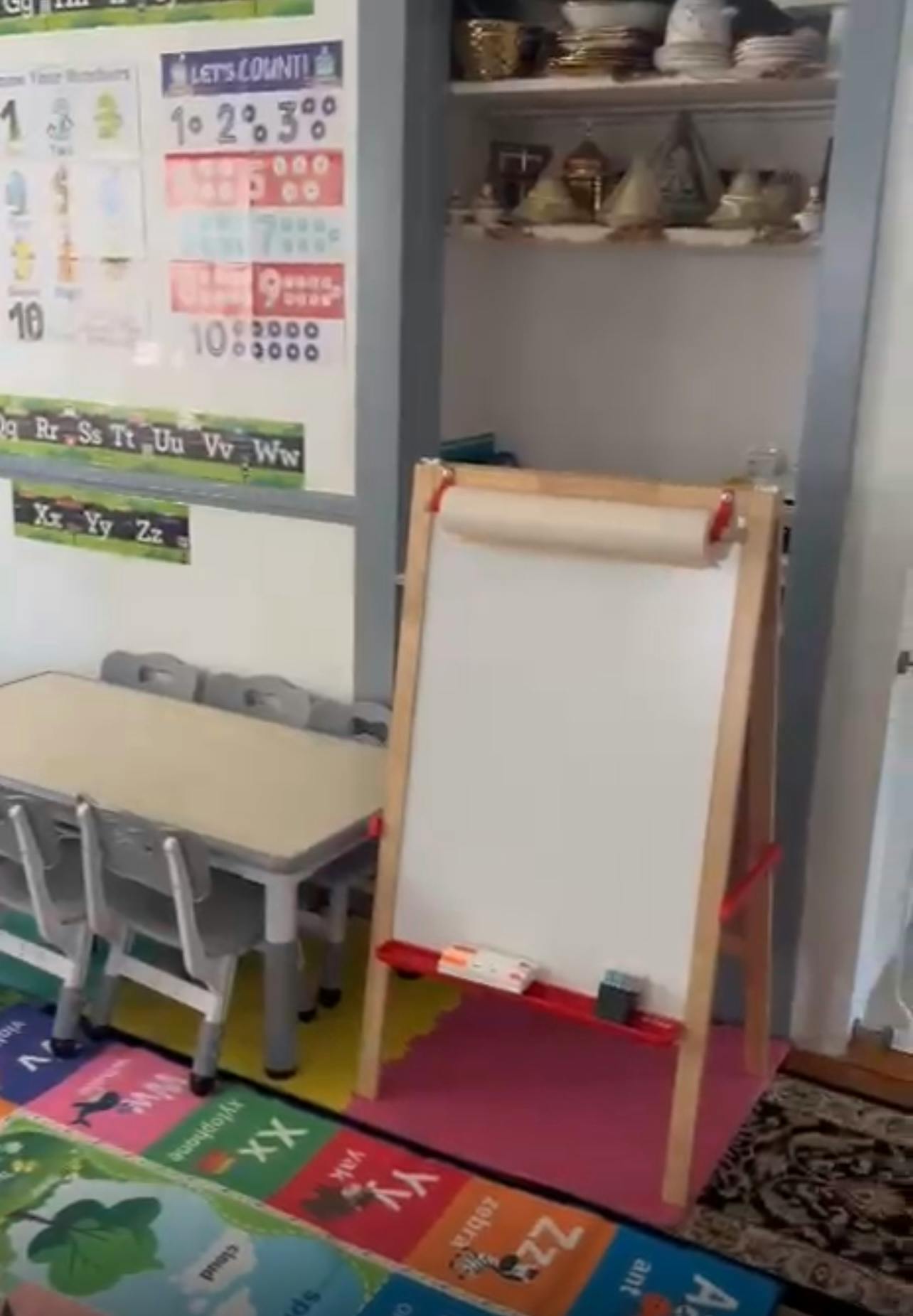 Easel with paper roll and whiteboard in a classroom with a table and chairs