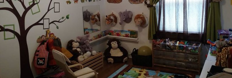 Playroom with stuffed animals, toys, and a tree decal on the wall