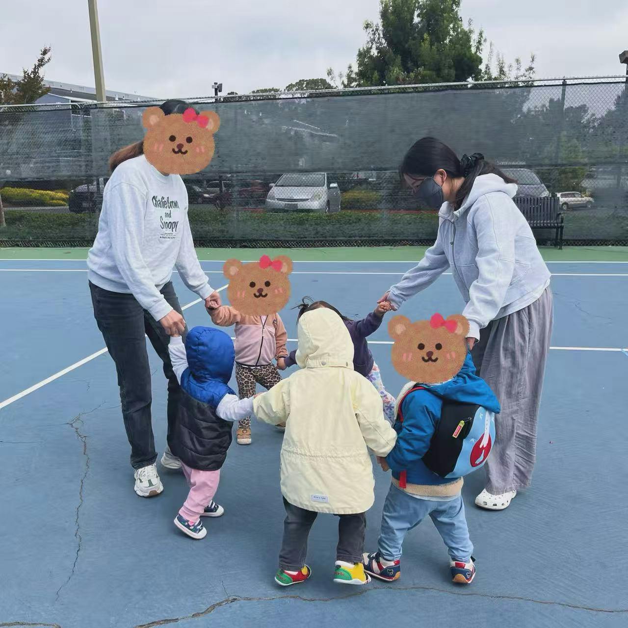 People holding hands with toddlers in a circle on a blue court