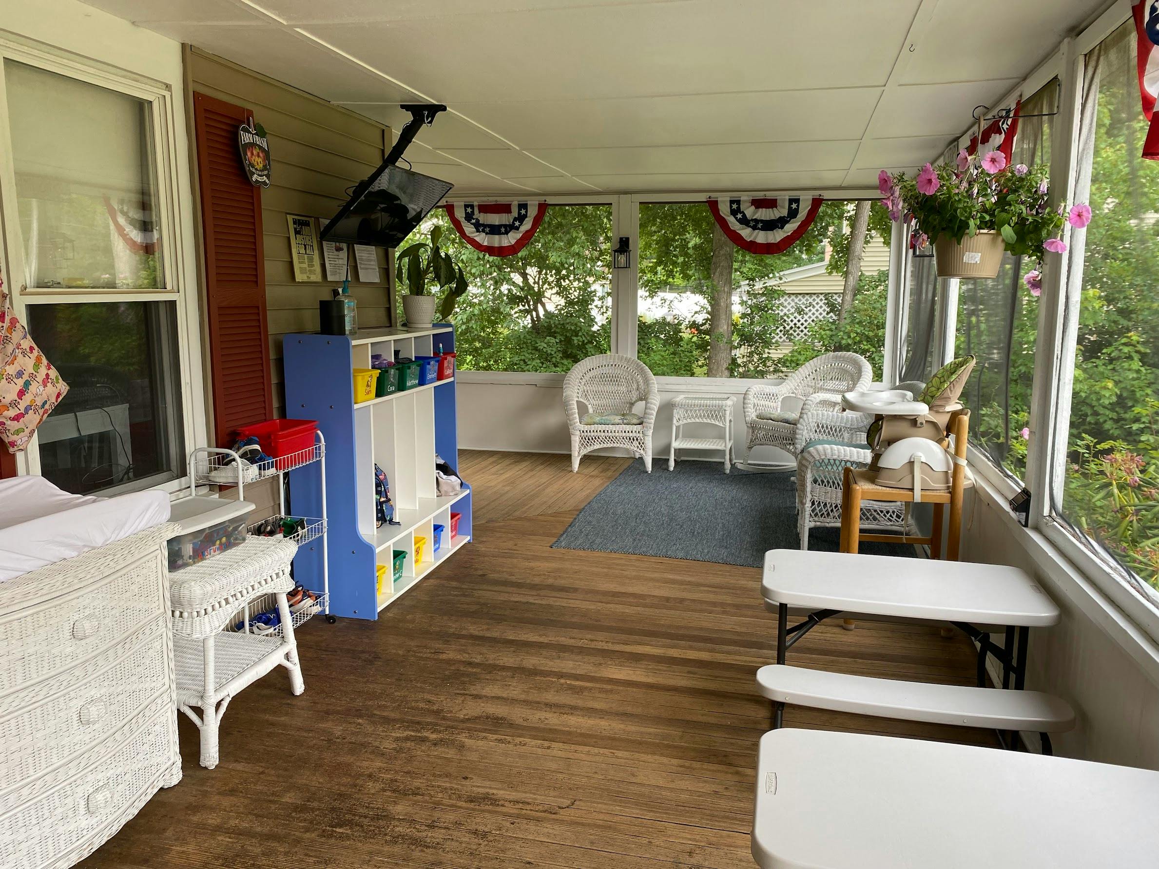 Sunroom with wicker furniture, blue storage unit, and small white tables