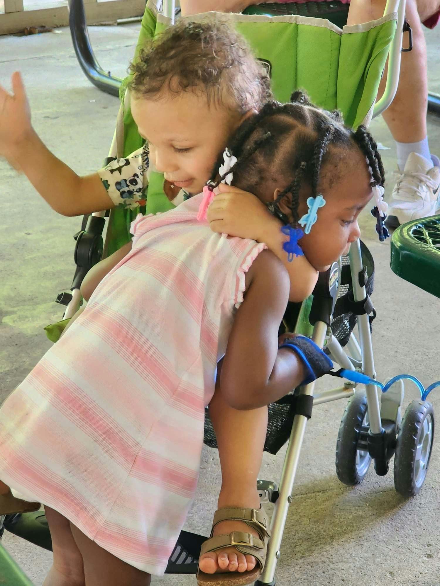 two children in a stroller hugging