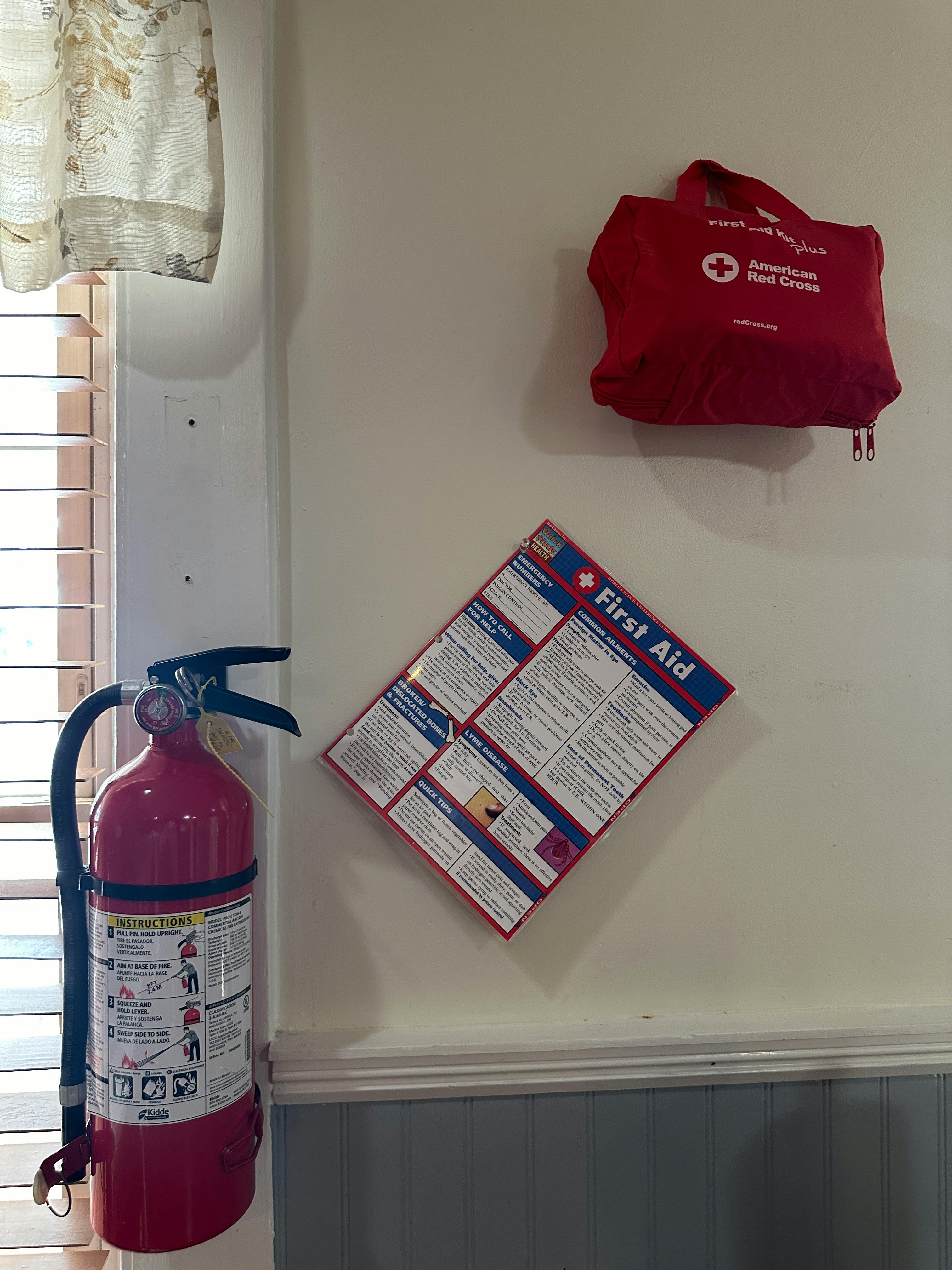 Fire extinguisher, first aid kit, and first aid instructions on a wall
