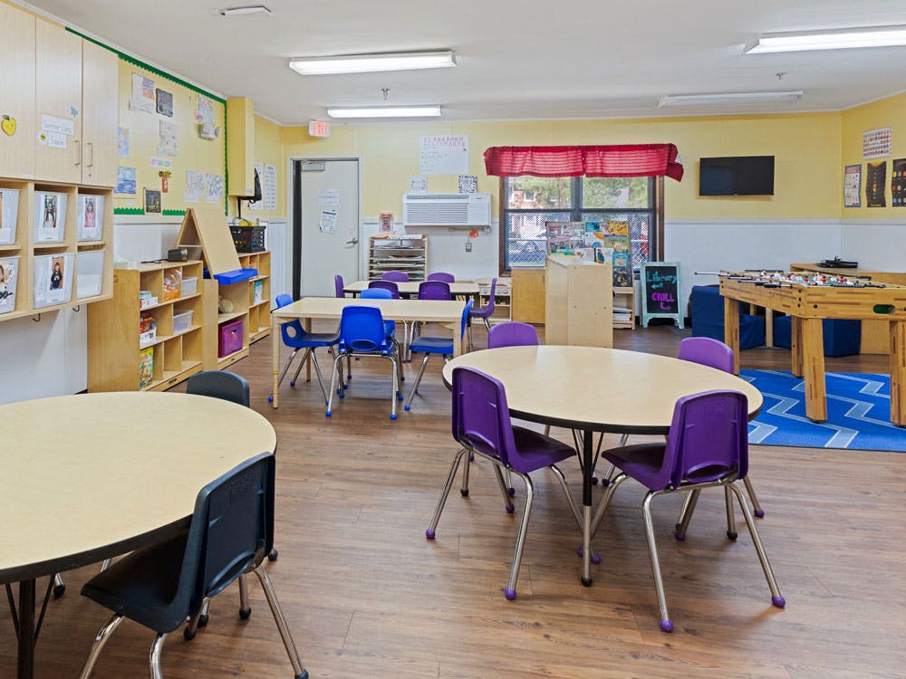 Classroom with small tables and chairs, and a foosball table