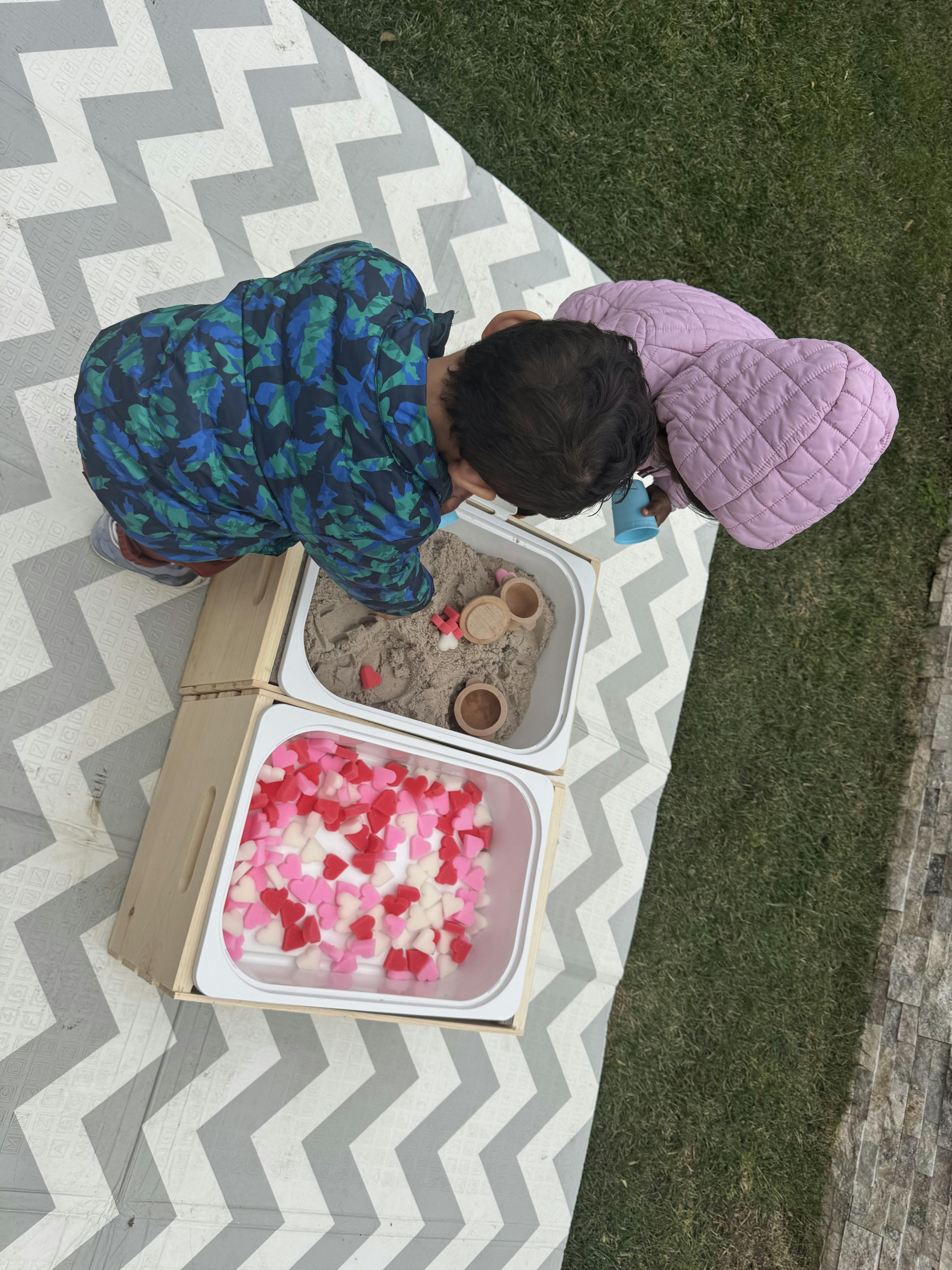 Child playing in sand and heart-shaped items