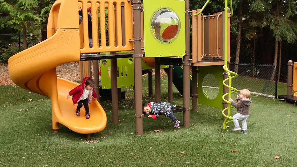 Three children playing on a playground structure