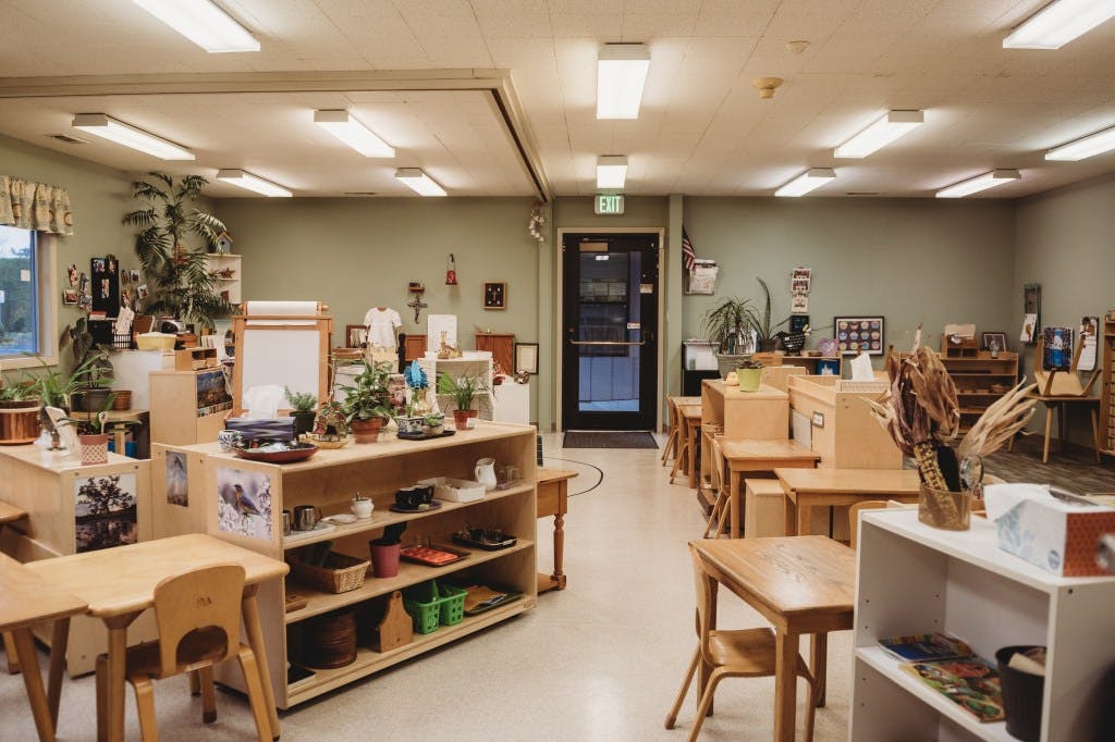 Classroom with small wooden tables and shelves