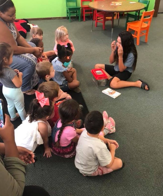 Adult and children sitting on floor in a classroom