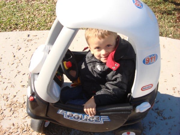 Child sitting in a toy police car