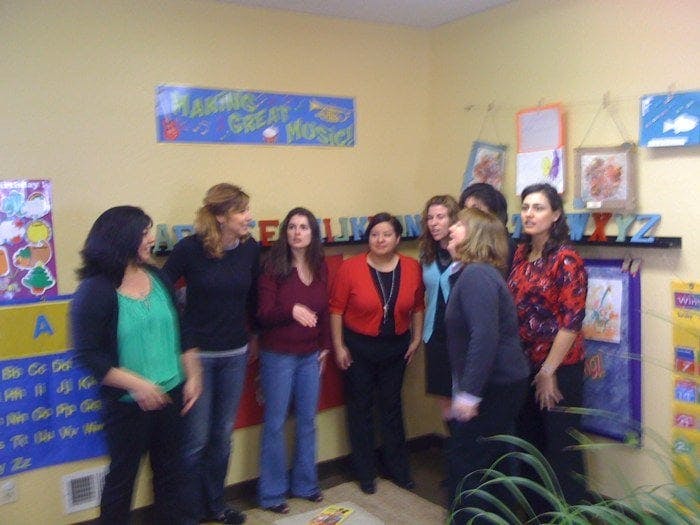 Group of people standing in a room with a banner on the wall