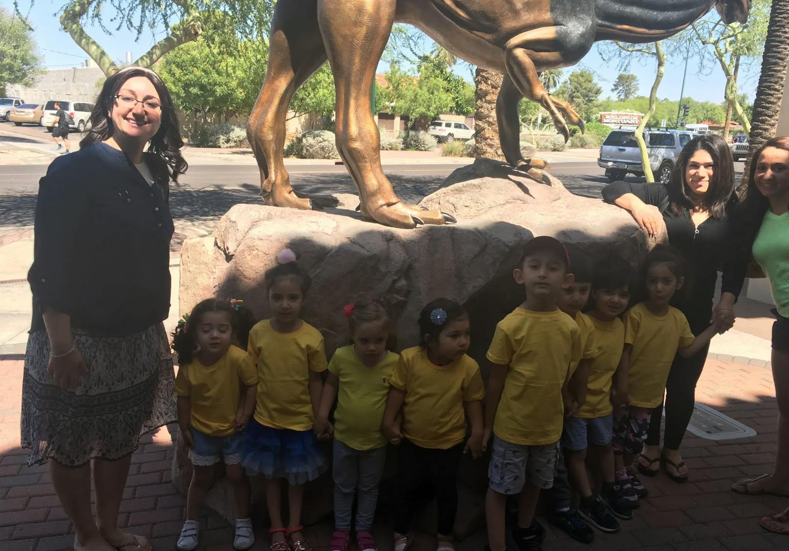 Adults and children standing in front of a large statue