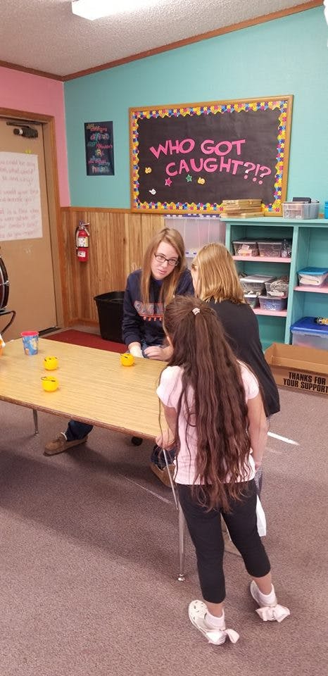 Three people gathered around a table in a classroom