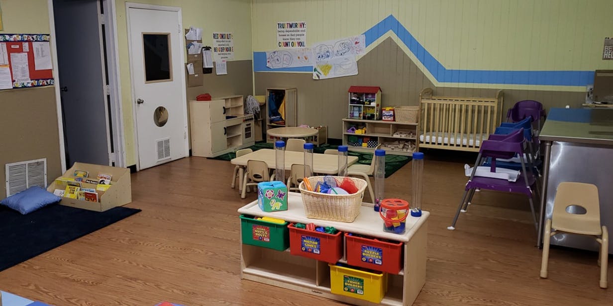 Childcare room with crib, tables, and toys