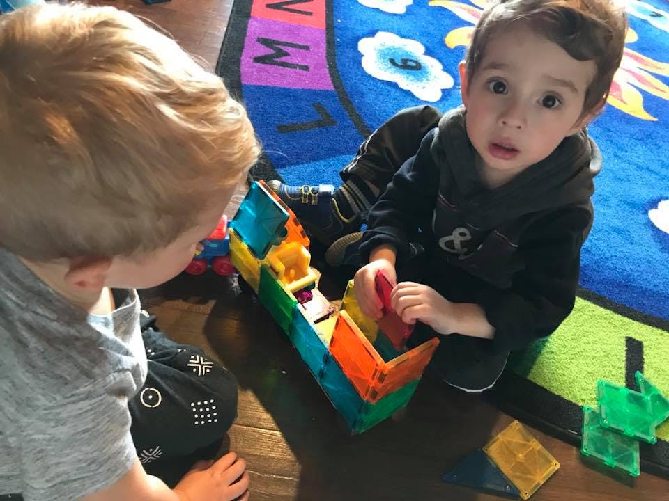 Two children playing with colorful magnetic blocks