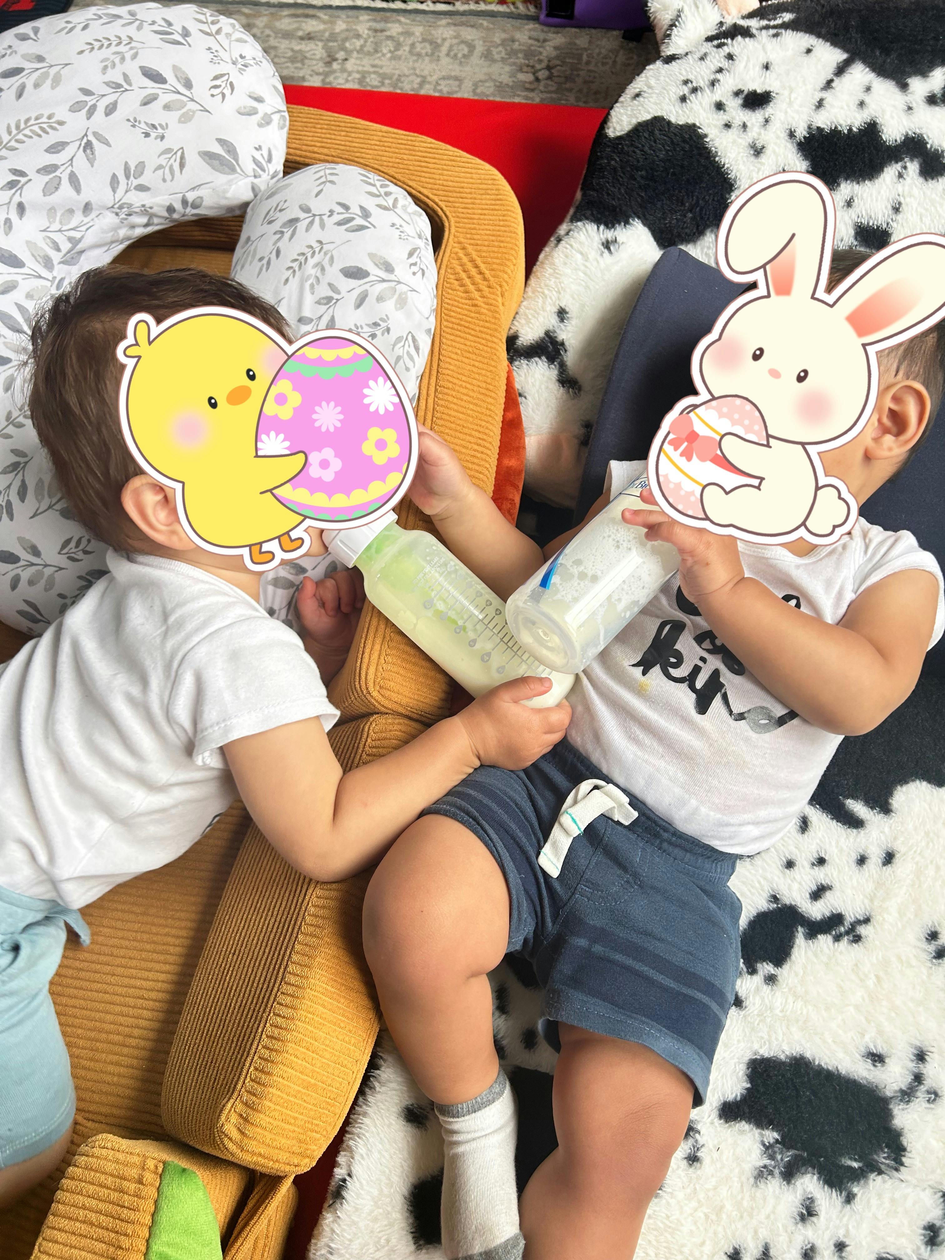 Two children lying down while holding baby bottles