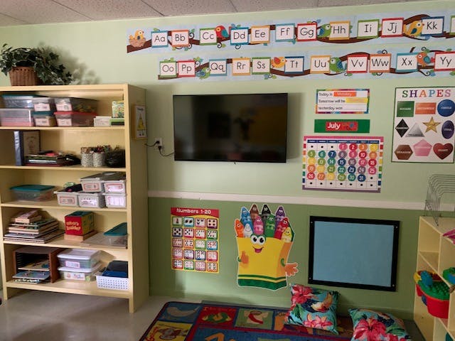 Classroom with alphabet banner, TV, calendar, and bookshelf