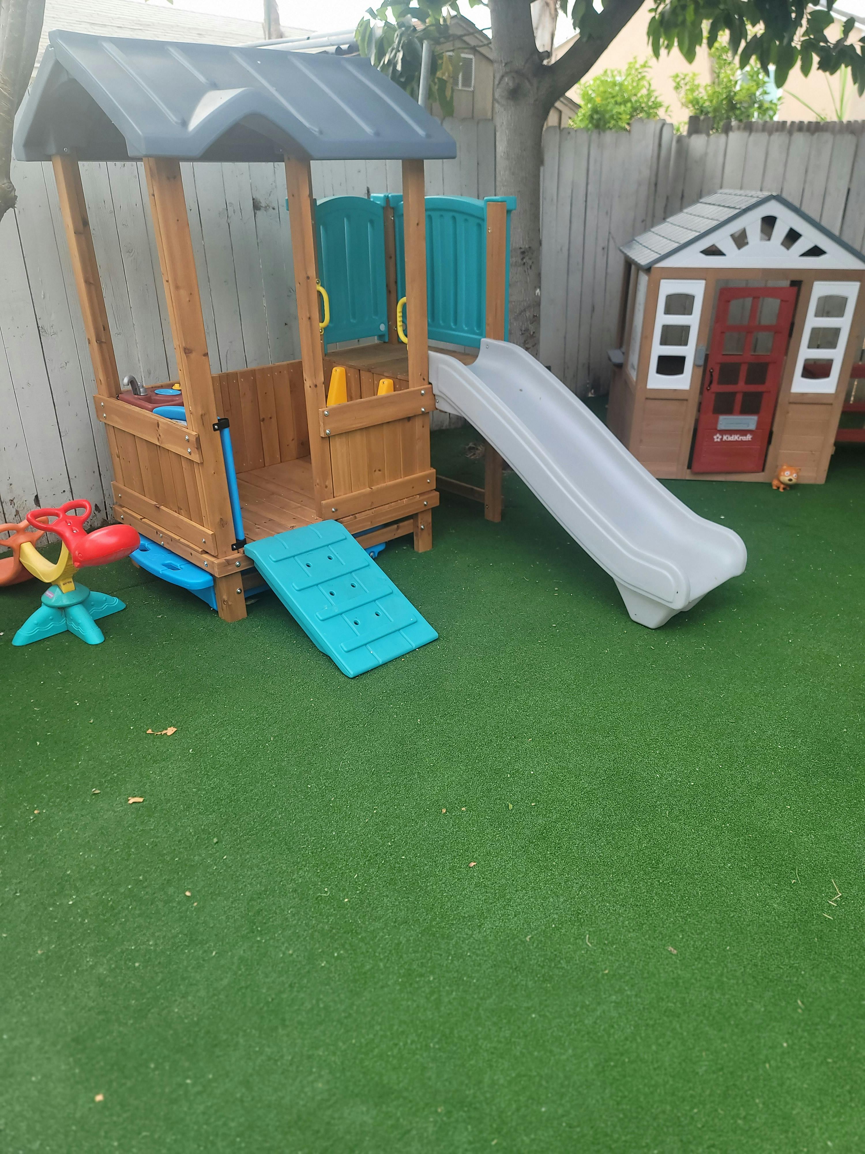 Playground with a wooden playhouse, slide, and a small play shed