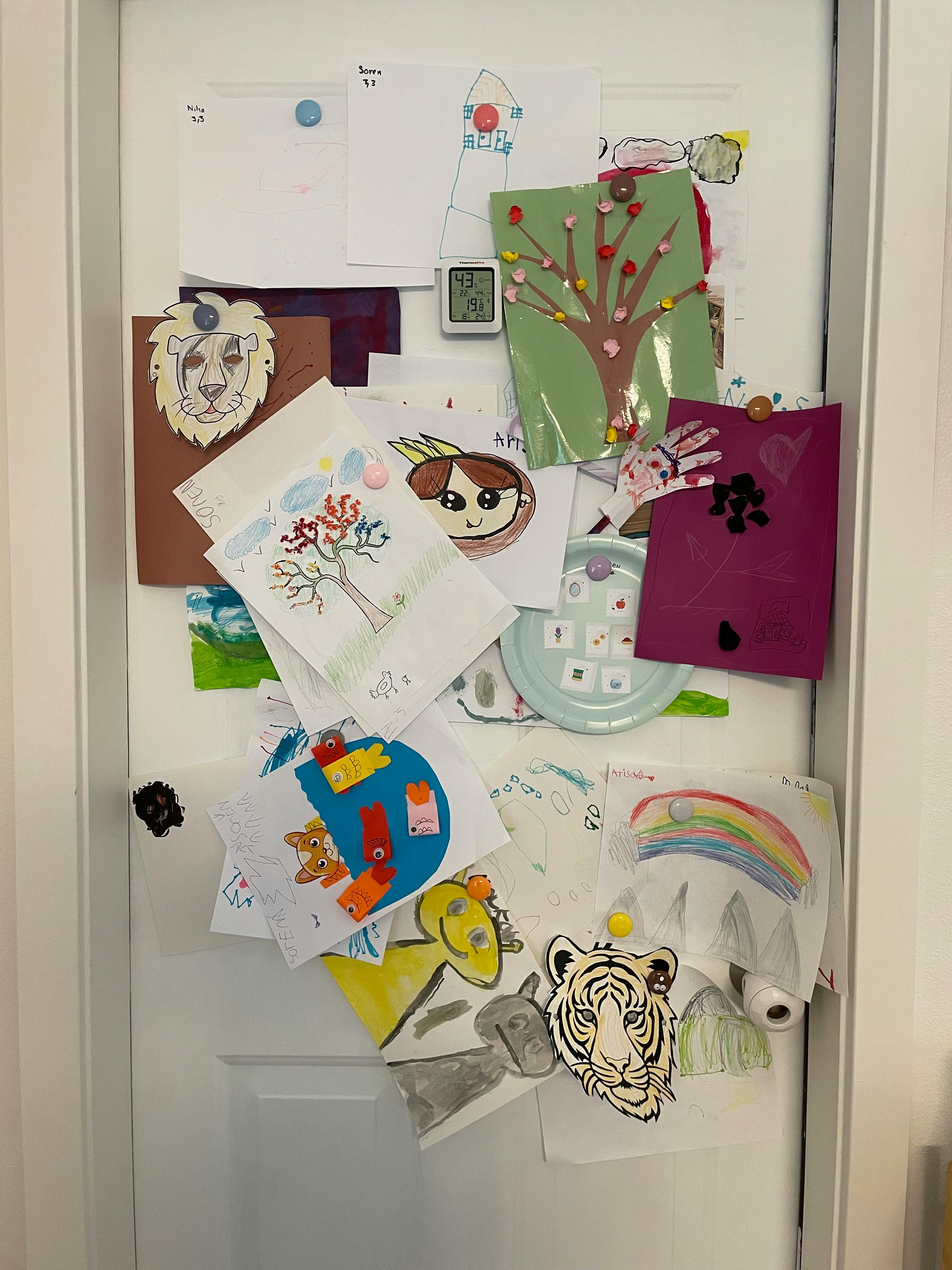 Children's artwork displayed on a white door
